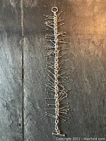 Full length shot of the sterling silver bracelet showing the chain with many dangling thin rod pins tipped with balls.