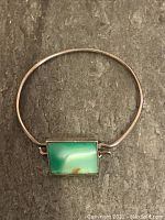 Full view of the vintage silver bracelet with a rectangular polished green and amber stone centerpiece.