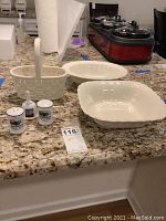 Overview photo showing all six items: two cream-colored bowls, ceramic basket, salt and pepper shakers, and novelty bell on kitchen counter.