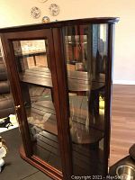 Overall angled view showing wooden frame, glass sides, and front door with brass knob.