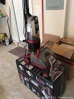 Upright Rug Doctor carpet and floor cleaner placed on box in garage.