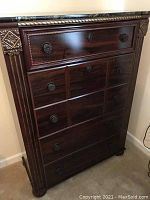 Frontal view of chest showing all five drawers, wood finish, and round metal knobs