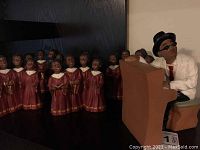 Photo showing one group of children choir figurines and the piano player man figurine seated at the piano.