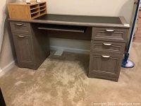Front view of gray composite wood desk with black vinyl inset top, drawers on both sides, and wood sorter on top left corner