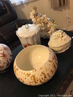 Photo showing five decorative glass pieces on a table including covered biscuit jars and decorative bowls.