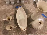 Photo showing oblong serving dish with gold trimmed handles and two small matching candle holder decorative pieces.