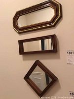 Three small wooden framed wall mirrors: octagonal with gold trim, rectangular, and square displayed as diamond.