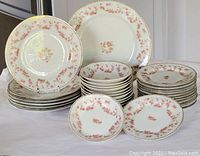 Set of stacked porcelain plates including dinner plate, salad plates, bread plates, and fruit nappies arranged to show quantity and pattern