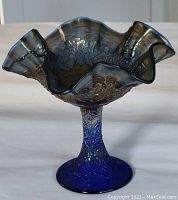 Side view showing cobalt blue color, ruffled edge, pedestal base, and Persian Medallion pattern.