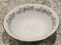 Top view of the round serving bowl showing the blue floral border inside and gold rim.