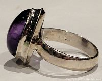 Close-up side view of sterling silver ring with oval amethyst gemstone showing polished band and large purple cabochon stone.