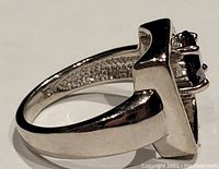 Side view of polished sterling silver band with garnet stone setting.