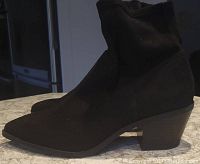 Side profile of a black suede short boot showing heel and pointed toe