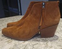 Side profile view of brown suede ankle boot showing pointed toe, side zipper, stacked block heel, and suede texture.