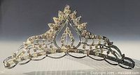 Front view of small sparkling tiara on silver-tone metal hair comb, showing detailed rhinestone arrangement and crown shape.