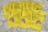Yellow sealed packets of TIVOLI Argan Oil Foot Masks and Hand Masks arranged on a surface. Includes several foot mask packages and hand mask packages, each one-time use.