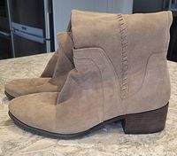 Side profile of light beige suede ankle boots showing whipstitch detail and stacked heel.