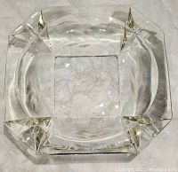 Top view of the vintage clear glass ashtray showcasing etched floral pattern in the center, etched leaves on the sides, and four holders around the edge.