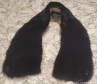 Dark brown mink fur collar laid flat on surface showing full length and fur texture.