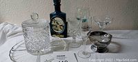 Photo of the glassware collection including the Jim Beam decanter with wildlife artwork, crystal ice bucket, various wine and crystal glasses, and a smokey glass candy bowl arranged on a white surface