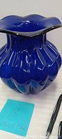 Close-up photo of large ruffle rim cobalt blue vase with a glossy finish and ruffled edges