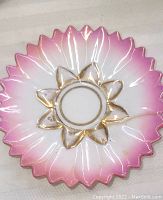 Close up of a pink and gold leaf scalloped-edge porcelain saucer with floral pattern in center