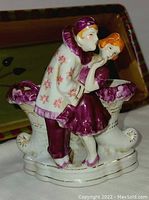 Porcelain figurine vase showing young couple; boy leaning in for kiss, girl turning head away.