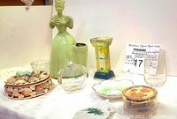 Full view of all items in the lot including figurine, trinket box, glass pumpkin jar, decorated plate, saucers, vase, and tumbler.