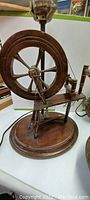 Close-up of Spinning Jenny style lamp showing wooden spinning wheel mechanism and wood base
