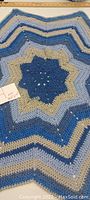 Close-up image of star-shaped multi-point crocheted blanket with blue, light blue, and cream colors.