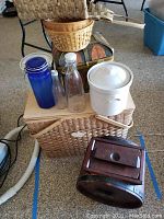 Photo of assorted baskets, crocks, glass bottles, canister, and a small wooden box stacked together
