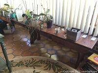 Photo showing two wooden benches with plants and miscellaneous items on one. Both benches appear to be the same style with a medium wood finish. One has a leaf inserted, the other shows the bench without the leaf part. Hexagonal tile floor and blinds in background.