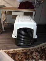 Front view of Petmate dog crate showing metal wire door and plastic construction with white top and olive-green bottom