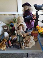 Full lot overview showing dolls, figurines, birdhouses, and the weathervane on a table