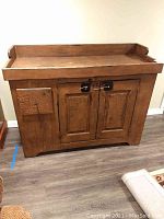 Full frontal view of the wood dry sink showing the drawer and double-door cabinet with metal latch closures, wood has visible wear and stains.