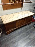 Front view of Lane wooden storage trunk bench with cushioned floral top showing scratches and stains on upholstery and wood.