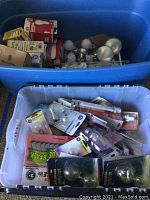 Two bins containing loose and packaged light bulbs of various types and sizes.