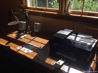 Desk setup including the lamp on the left, speakers, printer close to window, and mousepad visible on the wooden desk surface
