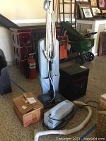 Oreck Type 7 upright vacuum standing upright with fabric bag and power cord, small box beside it, and black Eden Pure heater on floor