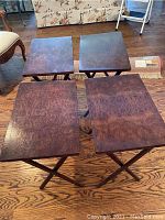Four burl wood TV tray tables arranged on a wooden floor showing the rectangular tray tops and wood grain pattern.