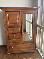Front view of wooden chifforobe dresser showing cabinet door, drawers, mirrored door, and bottom drawer.