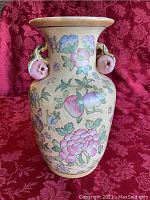 Full view of the ceramic vase showing the painted rose and pomegranate motifs on the cream-colored body and the flared rim.