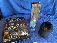 Photo showing two CU Boulder Football Vault collector's books, the Orange Crush bottle, and black CU baseball cap.
