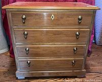 Front view of the wooden three drawer nightstand with acorn drawer pulls and decorative keyhole on top drawer.