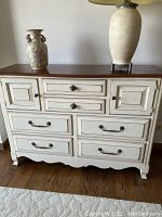 Front view of the dresser showing the antique white distressed finish, walnut top, and metal hardware.