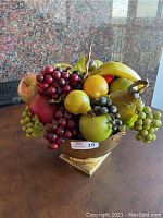 Full view of faux fruit arrangement in footed brass bowl.