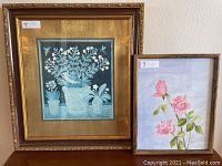 Two framed floral artworks, including a smaller painting of pink roses next to a larger floral print with birds, both framed.