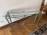Full view of glass top sofa table with patina bronze metal base.