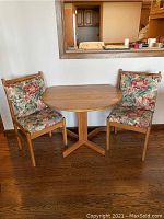 Photo of Michael Handler solid oak drop leaf table with both leaves down, flanked by two matching wooden chairs with floral upholstery.