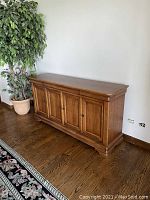 Full view of the light cherry finish buffet cabinet showing four doors and base molding.
